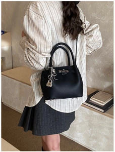 Vue détaillée du sac seau noir en cuir avec breloque argentée et fermoir pivotant en métal