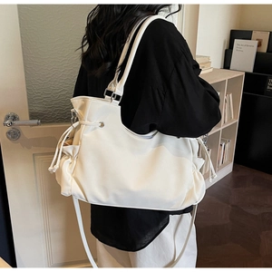 Detail view of large white tote bag with drawstring accents on a female model