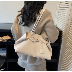 Rear view of model wearing a large cream shoulder bag with belt detail and twin straps