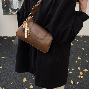 Détail d'un sac porté épaule rétro marron foncé avec pendentif en perles de bois