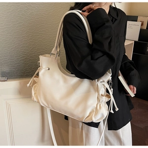 Detail of cream white tote bag with side drawstring pleats and adjustable strap