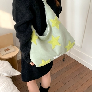Detail of light green fleece hobo bag featuring large yellow star and spacious interior