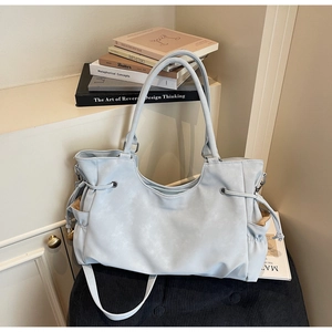 Detail of light blue drawstring tote bag with detachable strap on a black corduroy cushion