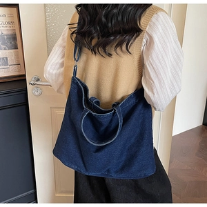 Deep blue denim tote bag shown worn by a model in a vintage interior setting