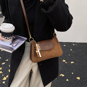 Détail du sac à bandoulière vintage marron avec texture mate et perles en bois