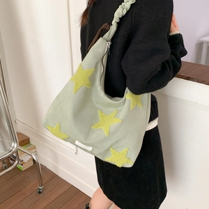 Detail of mint green hobo bag featuring yellow plush stars and a ruched shoulder strap