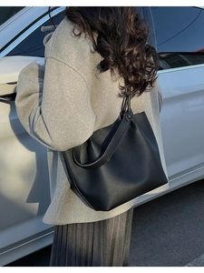 Outdoor shot of a black pebbled leather bucket tote bag with spacious minimalist design