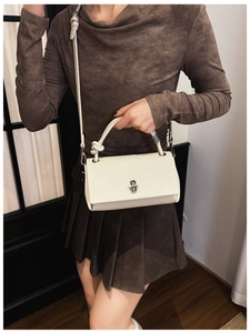 Detailed shot of white lychee leather handbag with silver clasp and knot handle detail