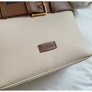 Dettaglio macro di una borsa tote in similpelle beige con cinturini marroni e oro