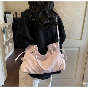 Detail of pink tote bag with drawstring sides and detachable strap shown on a model