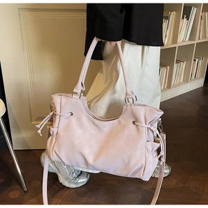 Detail view of large mauve tote bag featuring side drawstrings and smooth PU leather texture