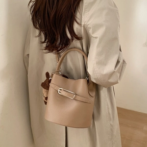 Détail du sac seau beige avec texture litchi et pendentif ours en peluche mignon