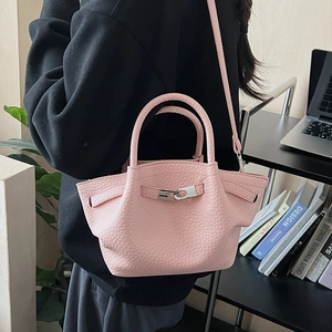 Détail d'un sac seau rose avec texture grainée et boucle métallique élégante pour femme