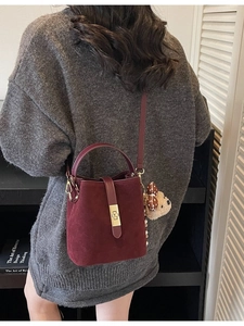 Sac seau rétro bordeaux en daim avec fermoir doré et breloque ours porté par un modèle