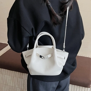 Détail d'un sac seau blanc à texture litchi avec fermoir en métal argenté et bandoulière