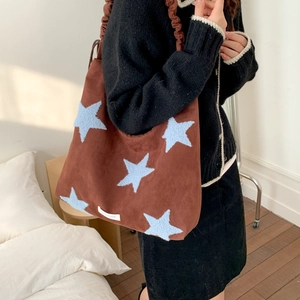 Detail of blue plush star patches on a brown faux suede tote bag with ruffled strap