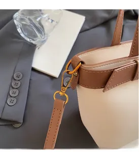 Dettagli dell'hardware dorato e delle cuciture su una borsa a secchiello bicolore