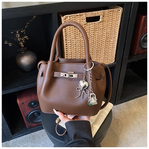Détail du sac seau en cuir litchi marron avec fermoir tournant argenté et breloque cœur