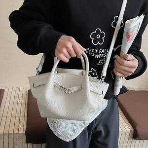 Gros plan du sac seau crème en cuir grainé avec détail d'anneau métallique