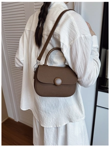 Detail view of a vintage-style brown saddle bag with canvas texture and leather trim