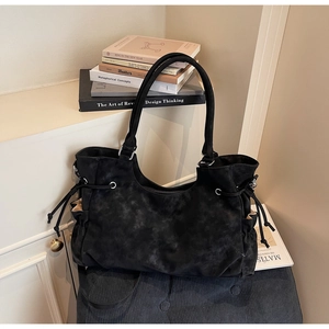 Detail of black matte tote bag featuring side drawstring accents and a vintage design