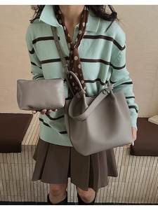 Close-up of a grey litchi texture bucket bag and matching pouch with a crossbody strap