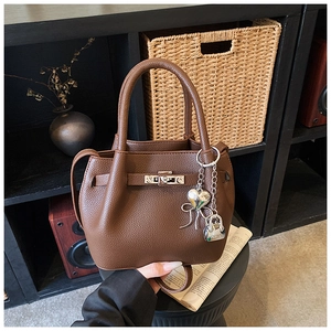 Détail du sac seau en cuir grainé marron foncé avec charms argentés et fermoir métal