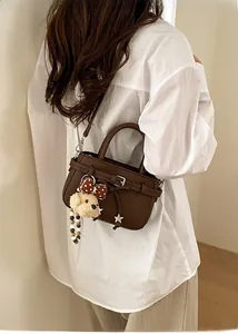 Detail of dark brown leather crossbody bag with cute puppy plush charm and silver hardware