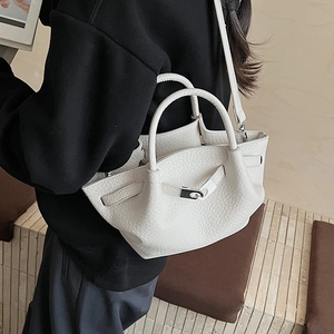 Détail du sac seau en cuir grainé blanc avec boucle argentée et bandoulière fine