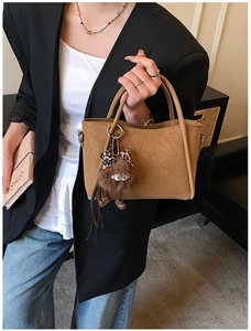 Close-up of brown bucket bag with grain texture and leopard print doll charm