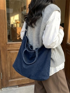 Deep blue denim tote bag with large capacity and shoulder strap worn by a model