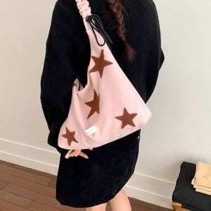Detailed view of pink plush crossbody bag featuring brown star patterns and ruched strap