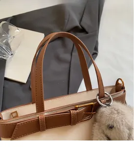 Dettaglio della borsa tote retrò con patchwork marrone e beige e ciondolo a forma di coniglio
