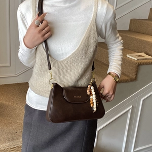 Détail du sac bandoulière en cuir mat marron foncé avec perles rétro et logo de marque