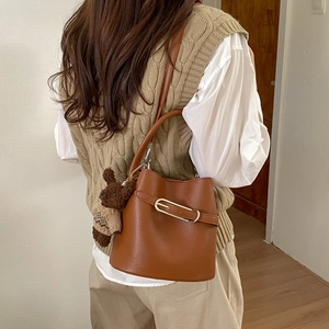 Sac seau marron en cuir grainé avec boucle argentée et pendentif ours sur modèle