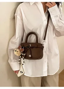 Detail of dark brown lychee texture mini bag with plush bear charm and star pendant