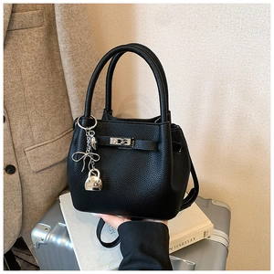 Détail du sac seau noir en cuir grainé avec boucle argentée et pendentif de mode chic