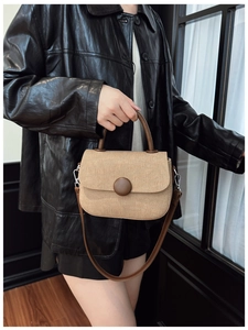 Detail of the vintage khaki canvas handbag with brown leather straps and round decorative buckle
