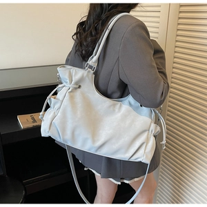Detailed view of matte beige tote bag featuring side drawstring design and metal eyelets