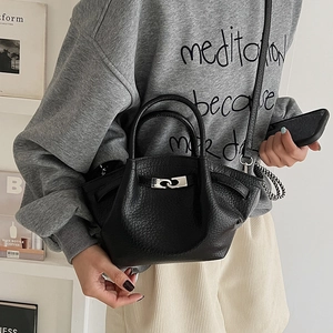Détail du sac seau en cuir grainé noir avec fermoir métallique argenté élégant