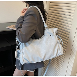 Detail of light blue tote bag showing side drawstring texture and wide shoulder strap