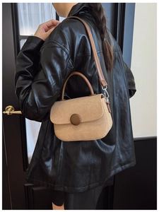 Modelo con bolso de lona beige con correas de cuero marrón en un entorno urbano interior