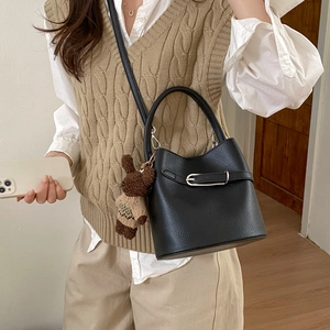 Détail du sac seau noir en cuir grainé avec boucle argentée et pendentif ours mignon