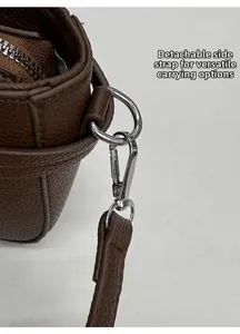 Detail of silver metal hooks and D-ring on brown litchi grain leather crossbody bag