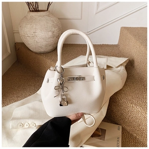 Détail du sac seau en cuir grainé blanc avec fermoir rotatif et pendentif coeur