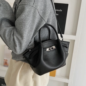 Détail d'un sac seau en cuir grainé noir avec fermoir tournant argenté et bandoulière
