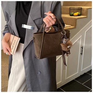Detail view of dark brown frosted suede bucket bag with a cute plush animal pendant