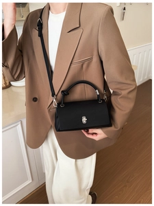 Close-up of black litchi pattern leather handbag with silver lock and knot handle detail