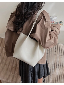 Close-up of white pebble-grain leather tote bag showing texture and adjustable strap details
