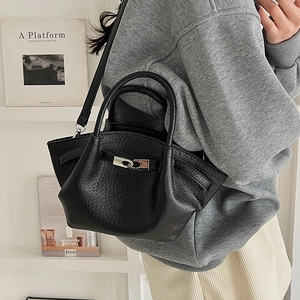 Détail du sac seau en cuir grainé noir avec fermoir métallique argenté entrelacé